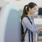 Frau benutzt Touchterminal am Flughafen