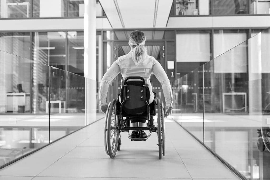 Frau im Rollstuhl im behindertengerechten Bürohaus | eKiosk