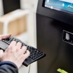 Mensch mit Tastatur vor Digital Signage Stele