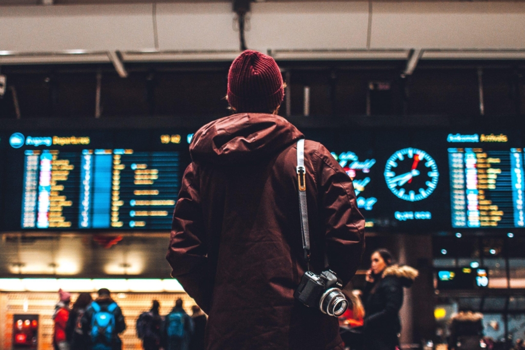 Mann am Flughafen ließt Anzeigetafeln
