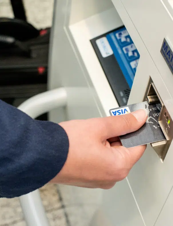 Hand steckt Geldkarte in Aufladeautomat