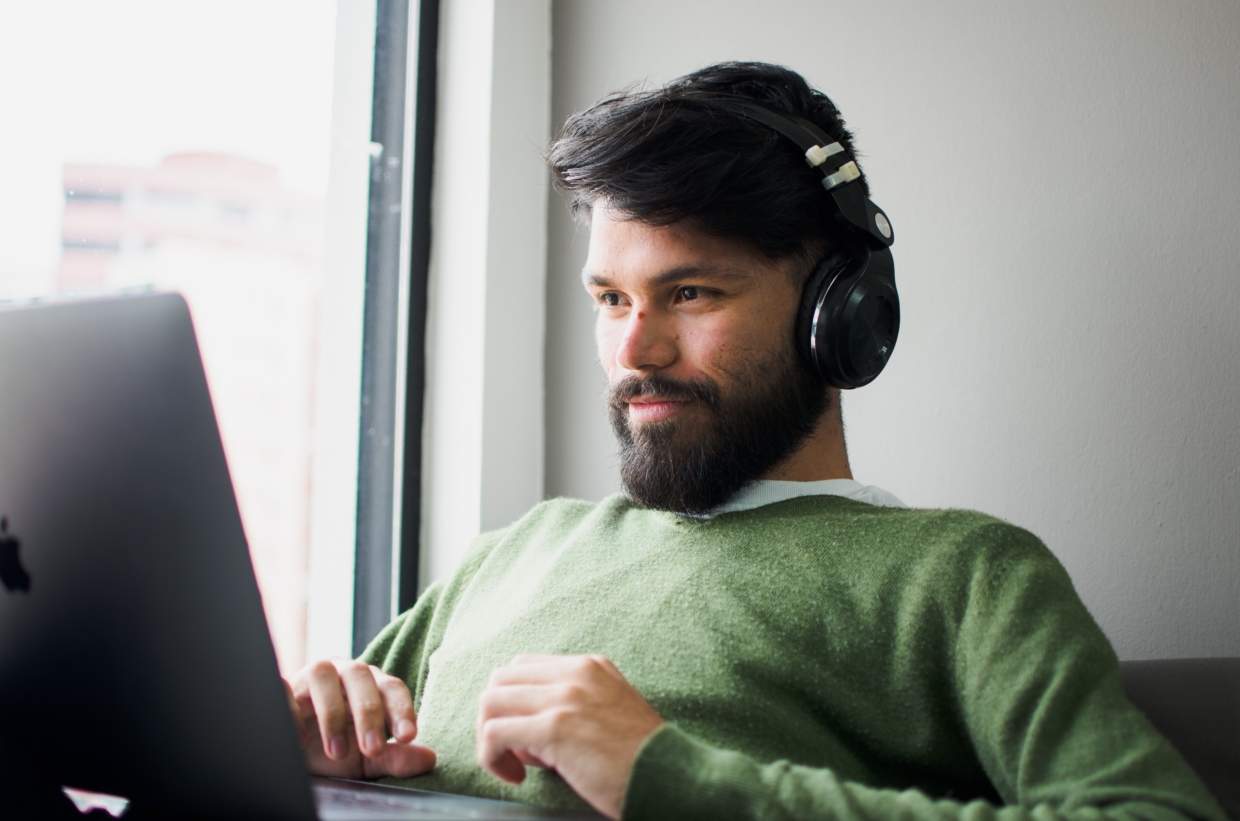 Mann mit Kopfhörern vor seinem Laptop