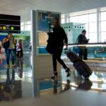 Ein Flughafengate mit Personen und einer digitalen Anzeige im Hintergrund